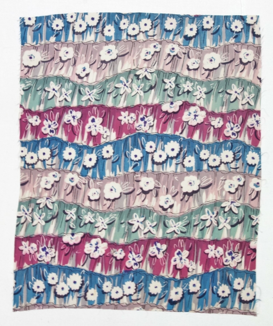 Sample of printed cloth with rows of stylised flowers in grass in blue, magenta, pink, grey and pale green on a white ground.