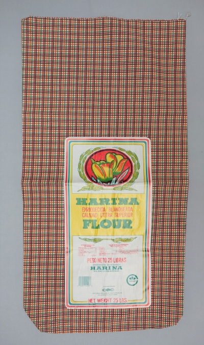 Large sack made from cotton with a printed checked design in brown, dark red, green and orange. With barcode. USA, 1960's (TRC 2017.3013).