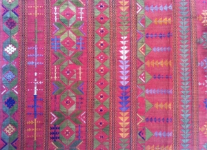 A detail from a piece of Suf embroidery. It is worked in floss silk thread on a magenta red cotton ground (India; mid-20th century).