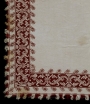 An example of 18th century Cyprian red work embroidery, possibly from Lefkara. The image shows the corner of a bed cover. It is made from linen that is embroidered with dark red silk using long-armed cross stitch, italian cross stitch, double running stitch and satin stitch.