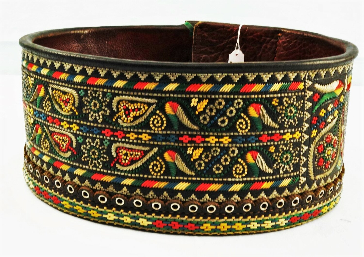 Belt made from a wide band of leather decorated with stylised floral and geometric motifs worked in coloured stripes of plastic using running and back stitches. There are also metal eyelets. Romania (Siebenburgen), 20th century (TRC 2016.0409).