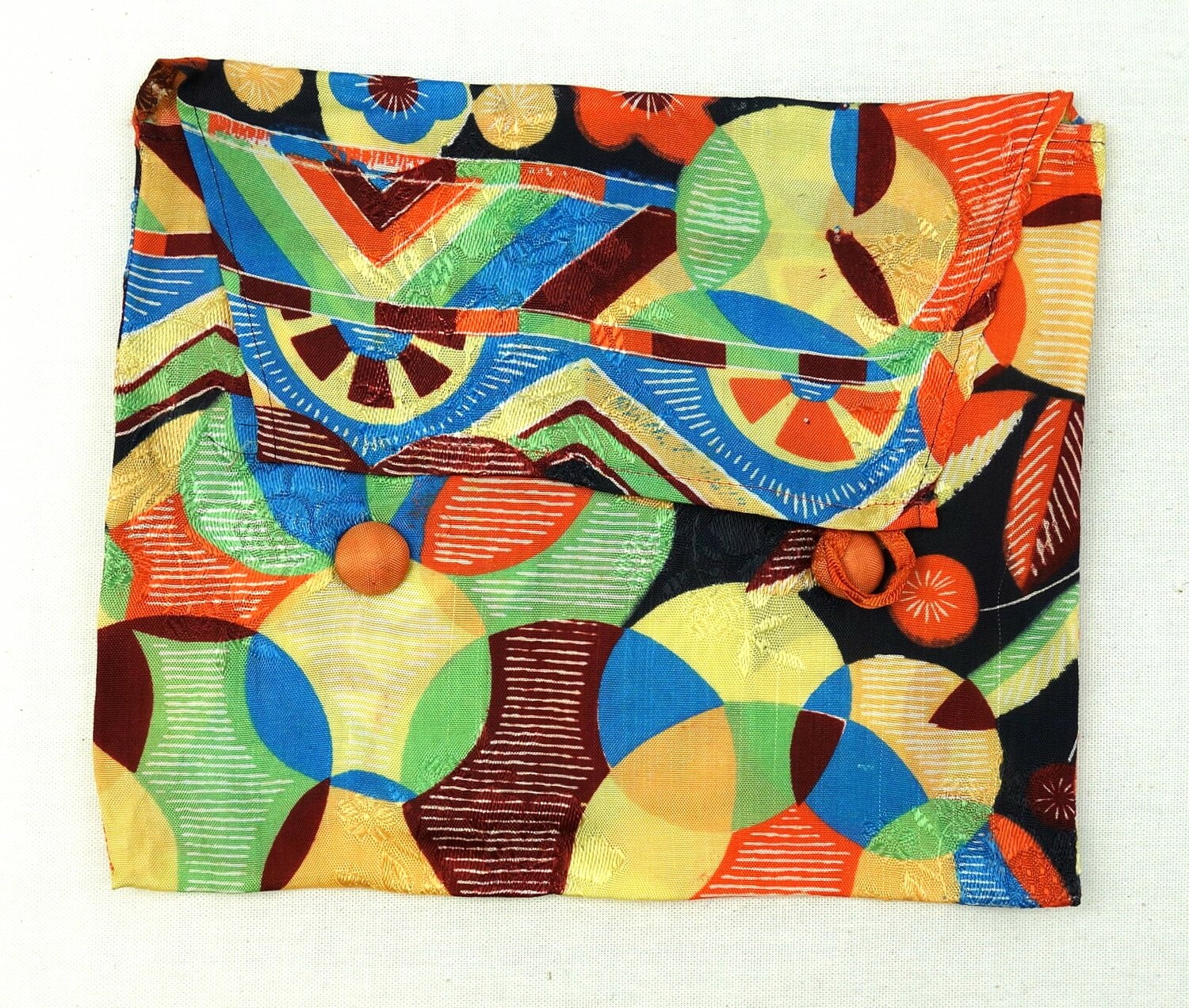 Small pouch decorated with a design of stylised flowers and circles. This type of pouch was used for storing silk lingerie and scarves. Made in Japan for the European market, 1930s (TRC 2016.2177).
