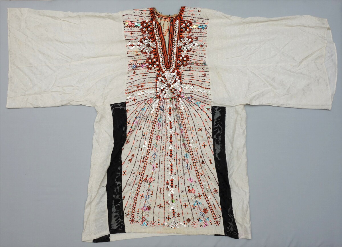 A white embroidered dress with applied buttons (ashera nauak; TRC 2017.2138).