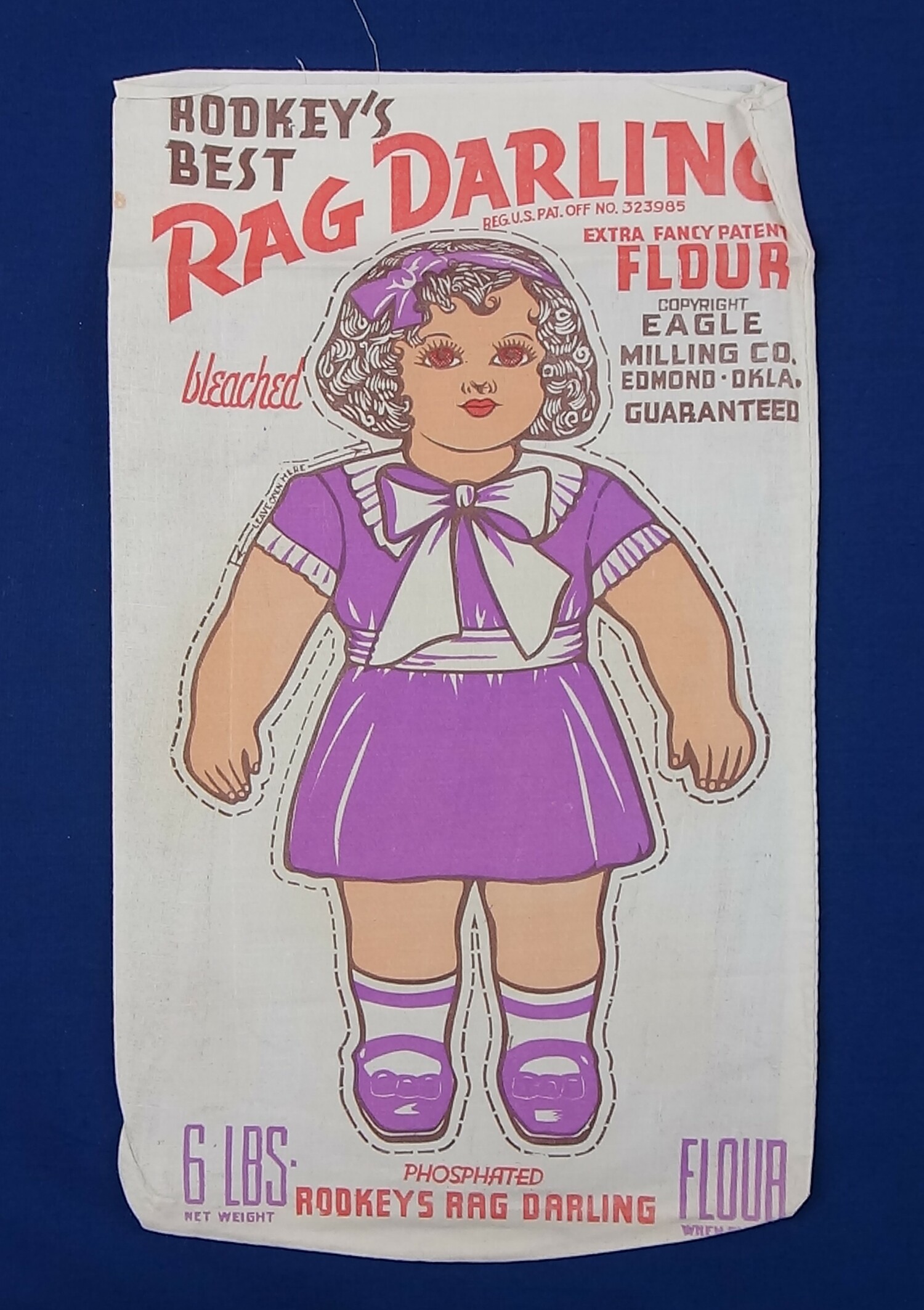 6lbs bag of extra fancy patent flour with a printed figure of a cloth doll wearing a purple dress. USA 1937 (TRC 2017.3232).