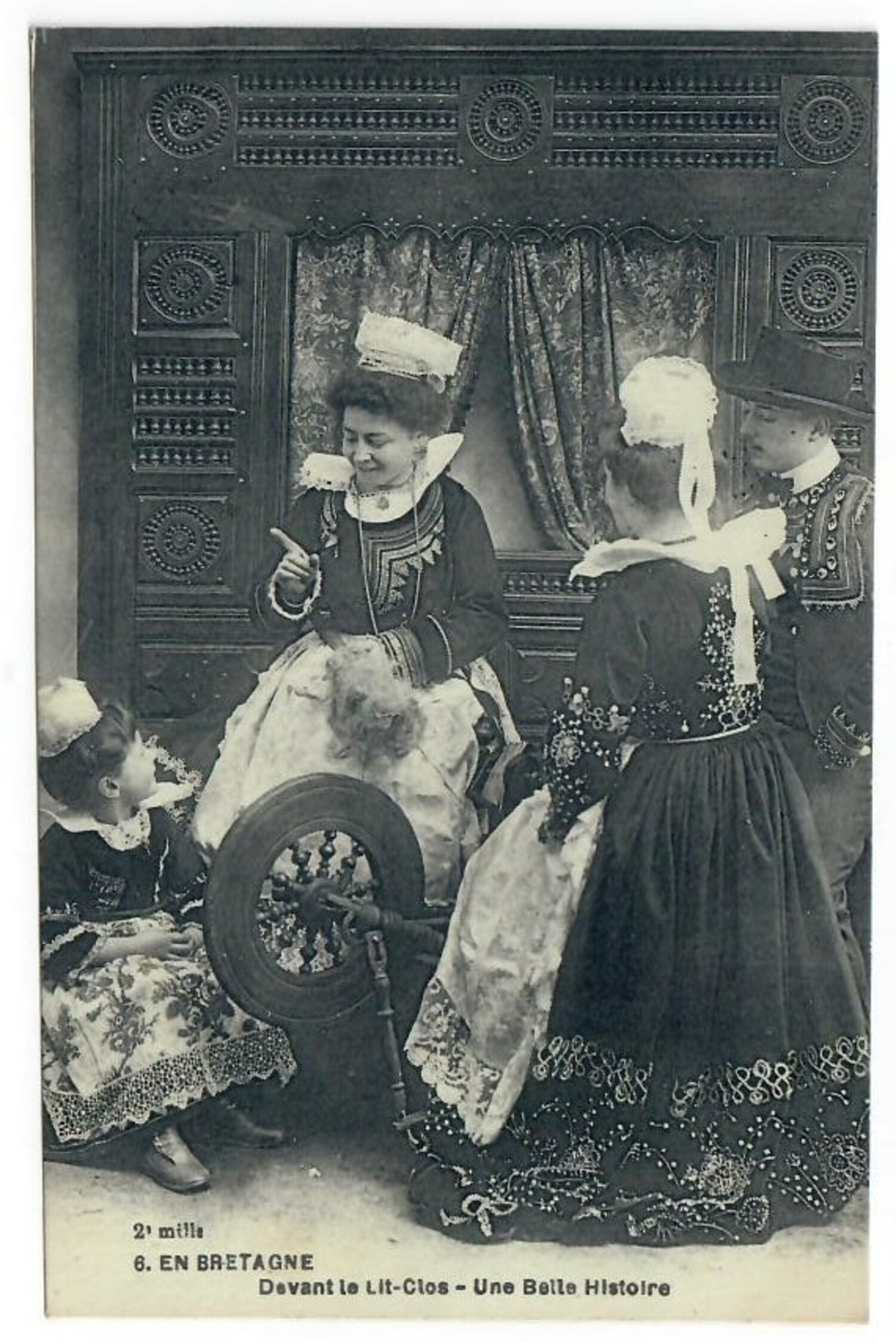 Postcard from France, early 20th century, depicting two women, a girl and a man wearing local dress. One of the women is seated next to a spinning wheel. There is a text on the front that states: "2 mille 6. EN BRETAGNE Devant le Lit-Clos - une Belle Histoire" (TRC 2020.4247).