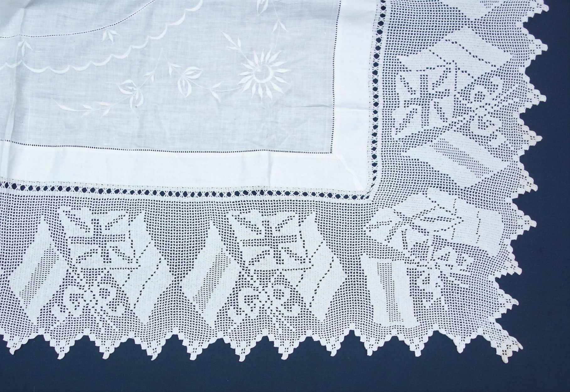 Corner of a linen tablecloth with a border design of three flag, with the Union Jack in the middle. Early 20th century (TRC 2020.3744).