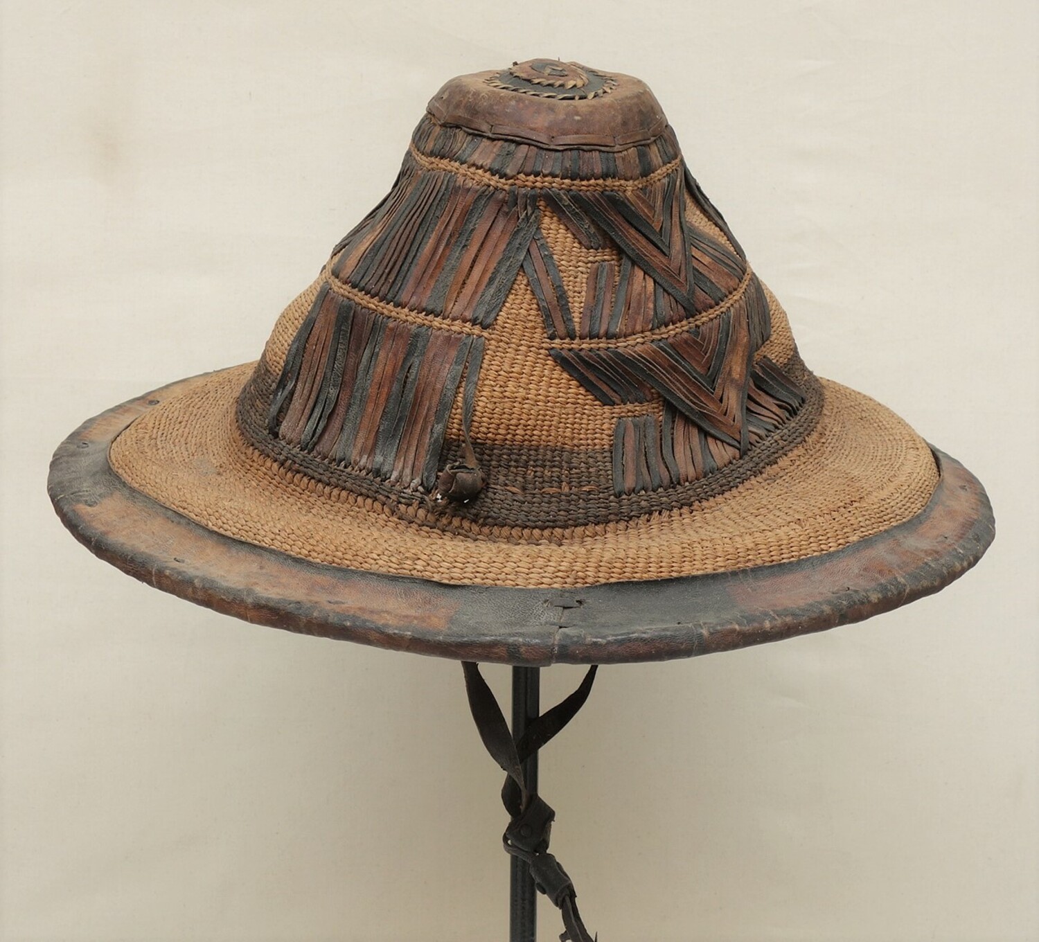 Straw or grass hat from West Africa, perhaps Togo, decorated with strips of leather (TRC 2021.1962).