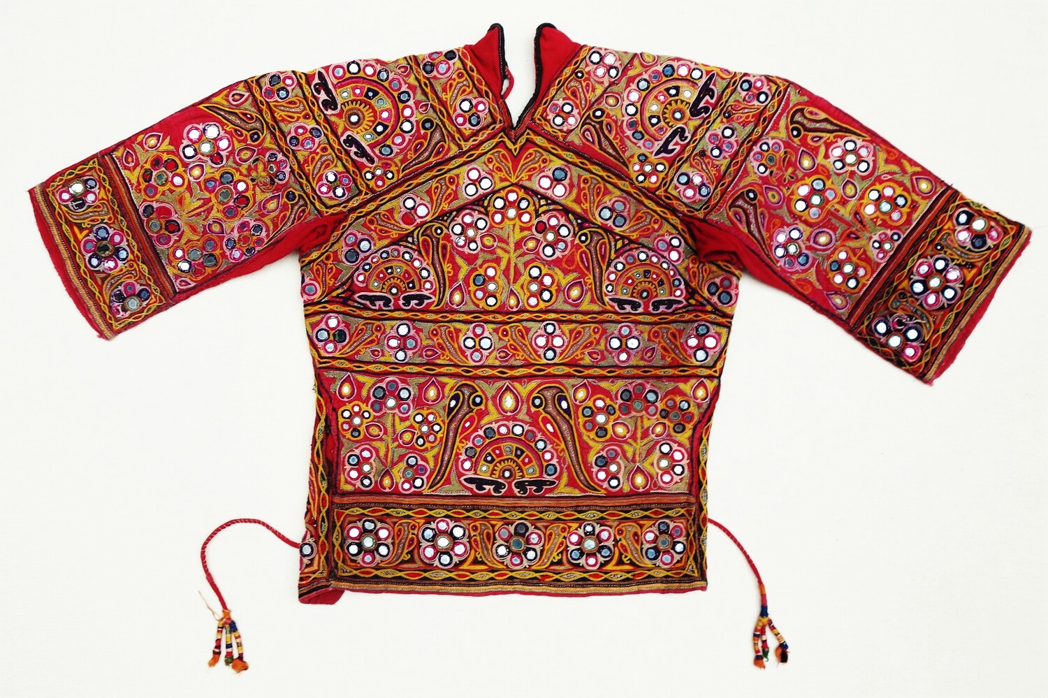 Embroidered bodice in red cloth decorated with stylised flowers, birds and geometric motifs, as well as applied circles of glass (shisha work). India, Gujarat, 20th century (TRC 2021.2222).