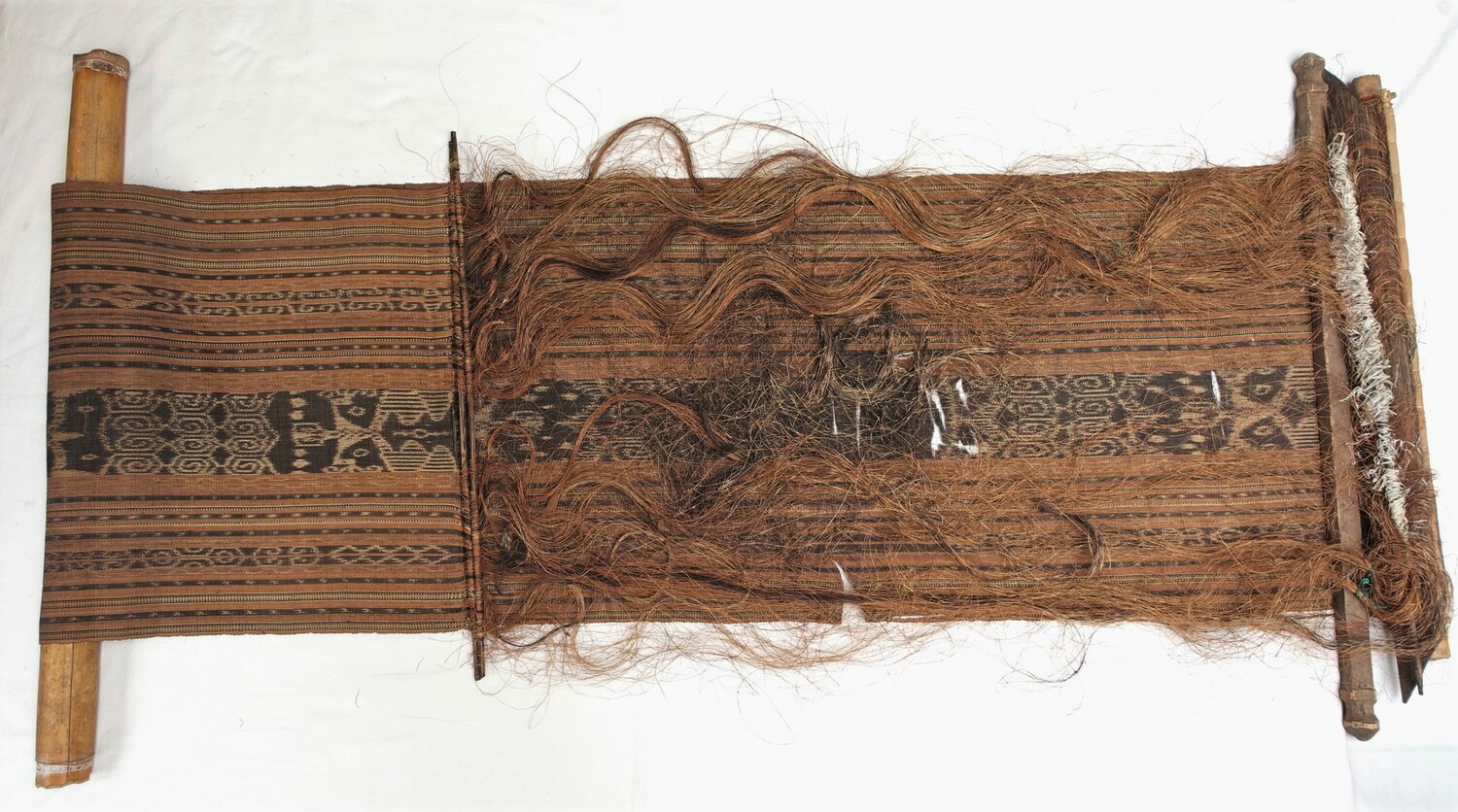 Back strap loom made of wood, with a length of ikat cloth made from abaca (Musa textilis), Philippines, mid-20th century (TRC 2021.3214).