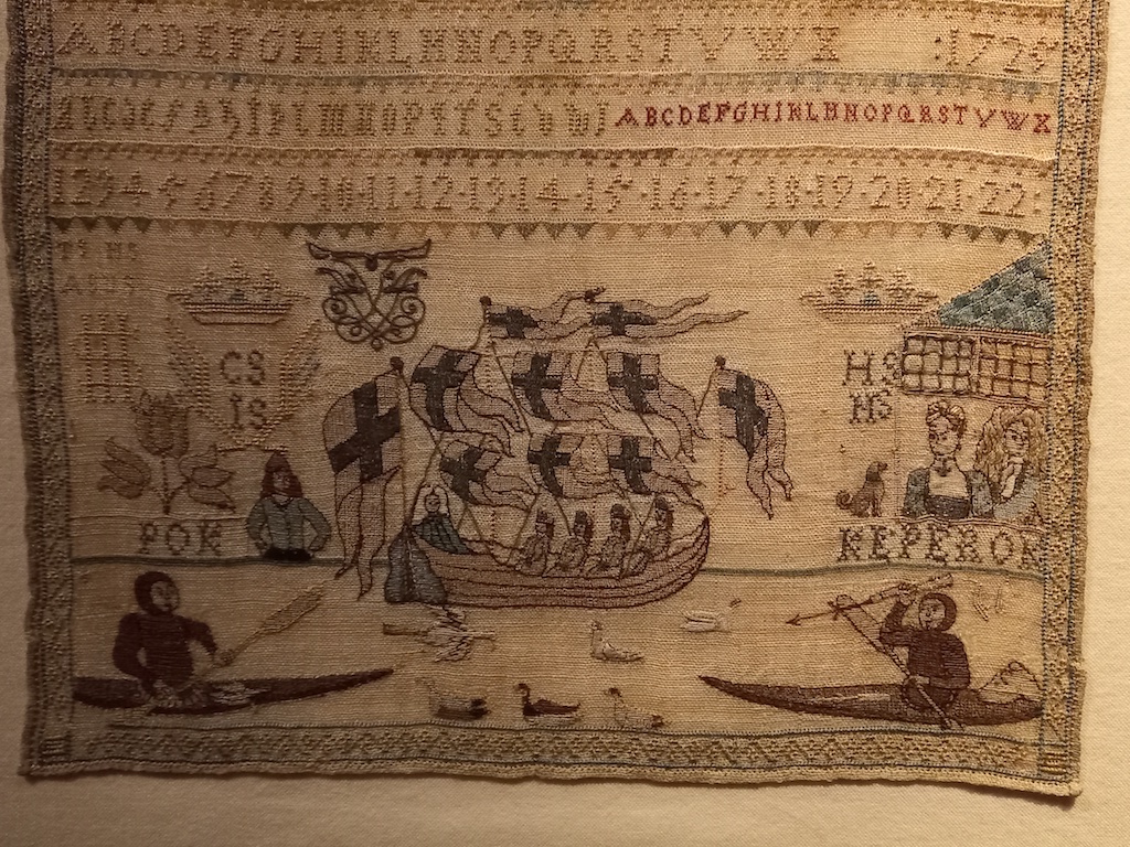 Sampler from 1725, recalling the scene of two men from Greenland (Pooq and Qiperoq) kayakking in Frederiksholm Canal in 1724. National Museum Copenhagen, acc. no. 136915/L18.495.
