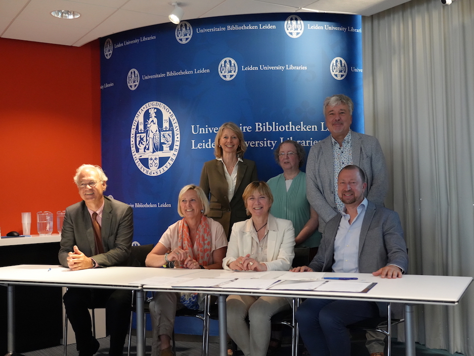 Official hand-over by the Ottow family of documents and textiles to the University Libraries and the TRC: Sitting behind the table: Prof. Annetje Ottow  (Chair, Leiden University Board, second from the left), and her husband (to the far left), sister (right), and brother (far right). Standing behind them, from left to right: Dr Alette Stas-Bax (Chair Leids Universiteitsfonds), Dr Gillian Vogelsang-Eastwood (Director Textile Research Centre), and Dr Kurt De Belder (Director Leiden University Libraries). Photograph by Guus Janssen, Leiden University Libraries.