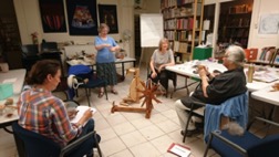 Figuring out how to spin a thread using spindle and spinning wheel. TRC Intensive Textile Course, August 2021. Photograph: Evelyn Valencia
