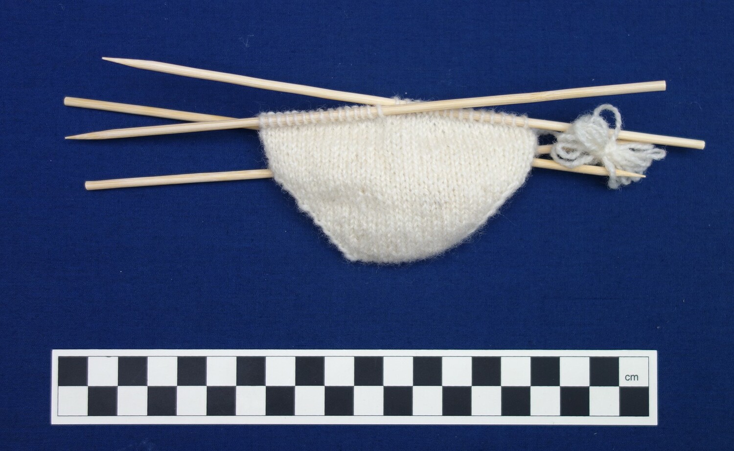 Knitted sample of a shaped toe with knitting needles in place (TRC 2019.1397).